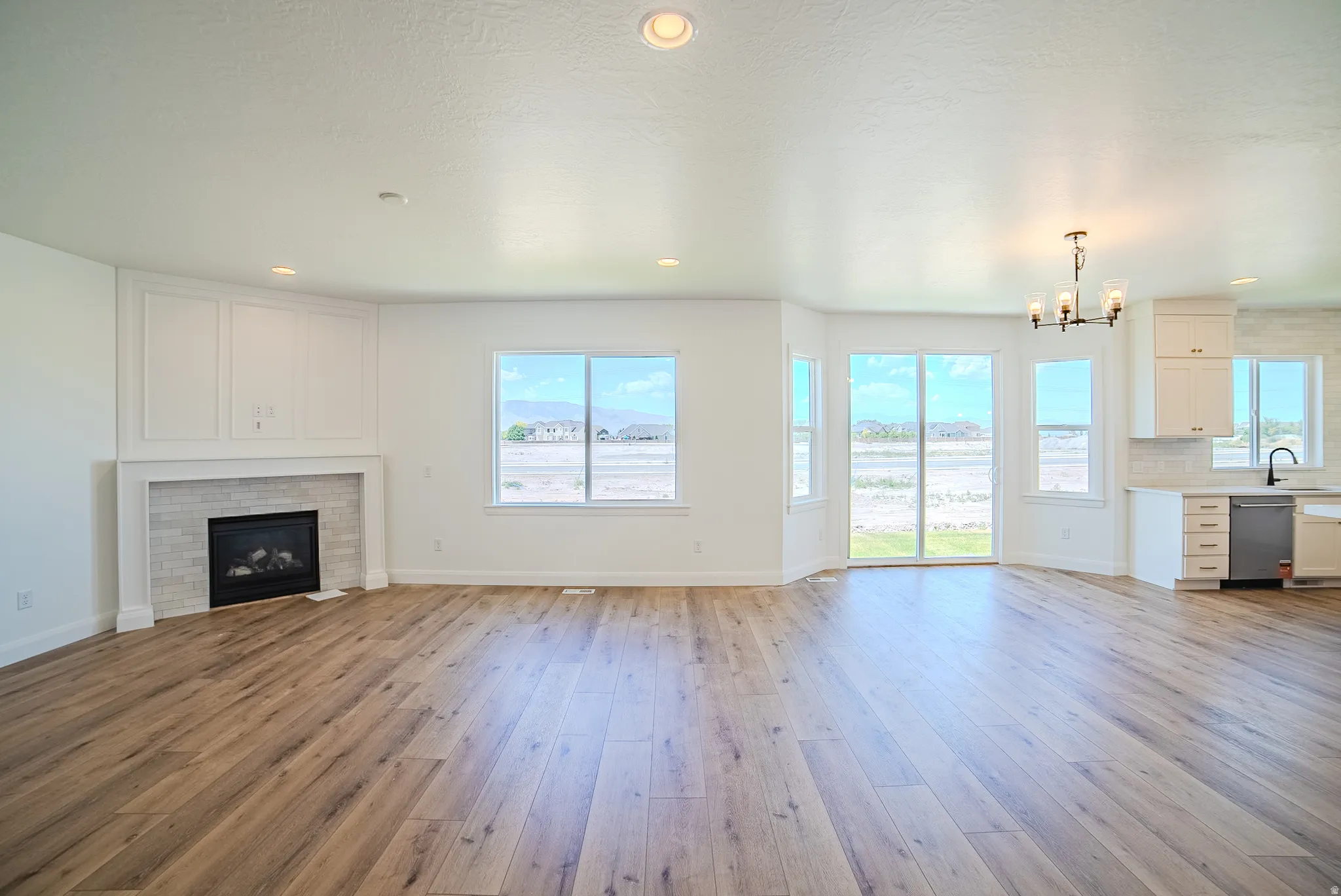 Open-concept living area featuring wood-finish flooring, a contemporary fireplace with tile surround, and an integrated kitchen space