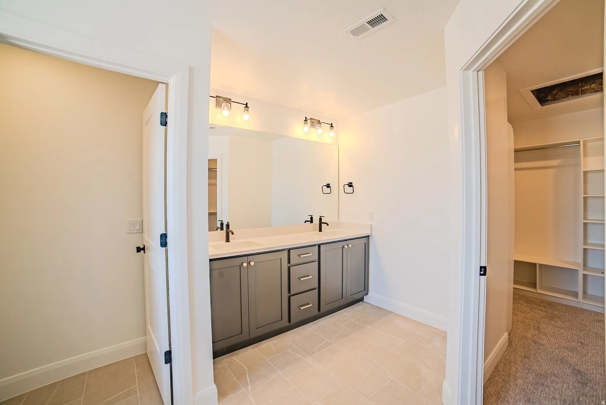 Contemporary bathroom featuring a double vanity with gray cabinetry, light-colored countertops, and matte black fixtures