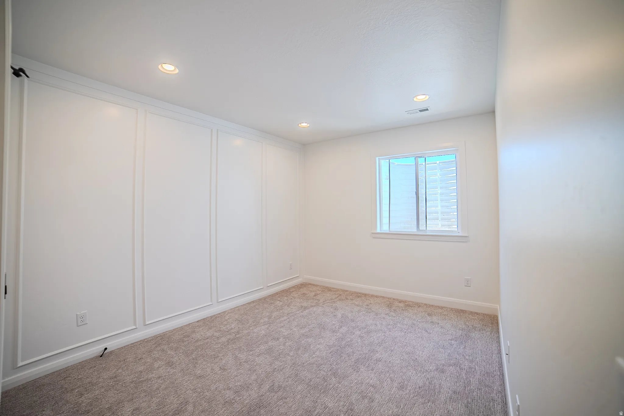 Recessed lighting illuminating a spacious room with light-colored carpeting