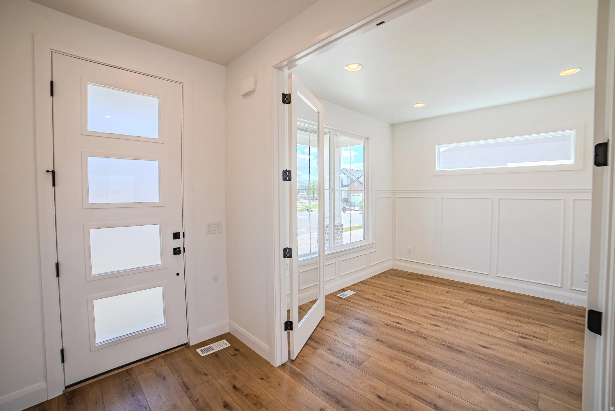 Entryway featuring a modern front door with frosted glass panels, wood-finish flooring, and recessed lighting