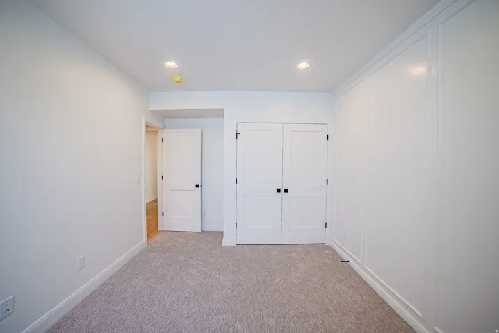 Bright interior room featuring a neutral carpet, recessed lighting, and a white paneled accent wall