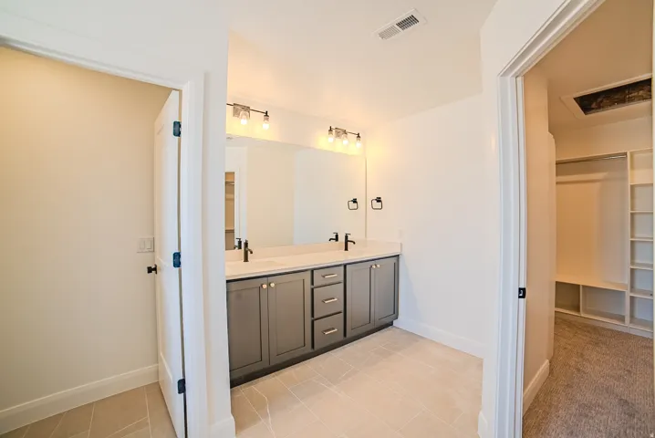 Contemporary bathroom featuring a double vanity with gray cabinetry, light-colored countertops, and matte black fixtures