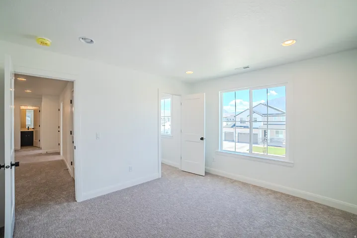 Spacious room featuring light gray carpet flooring, white walls, and a large multi-pane window