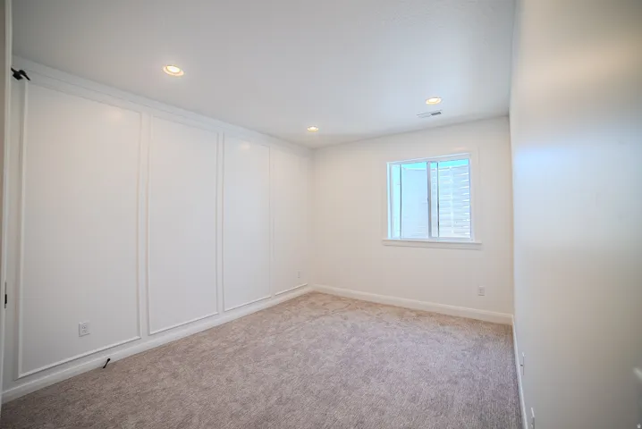 Recessed lighting illuminating a spacious room with light-colored carpeting