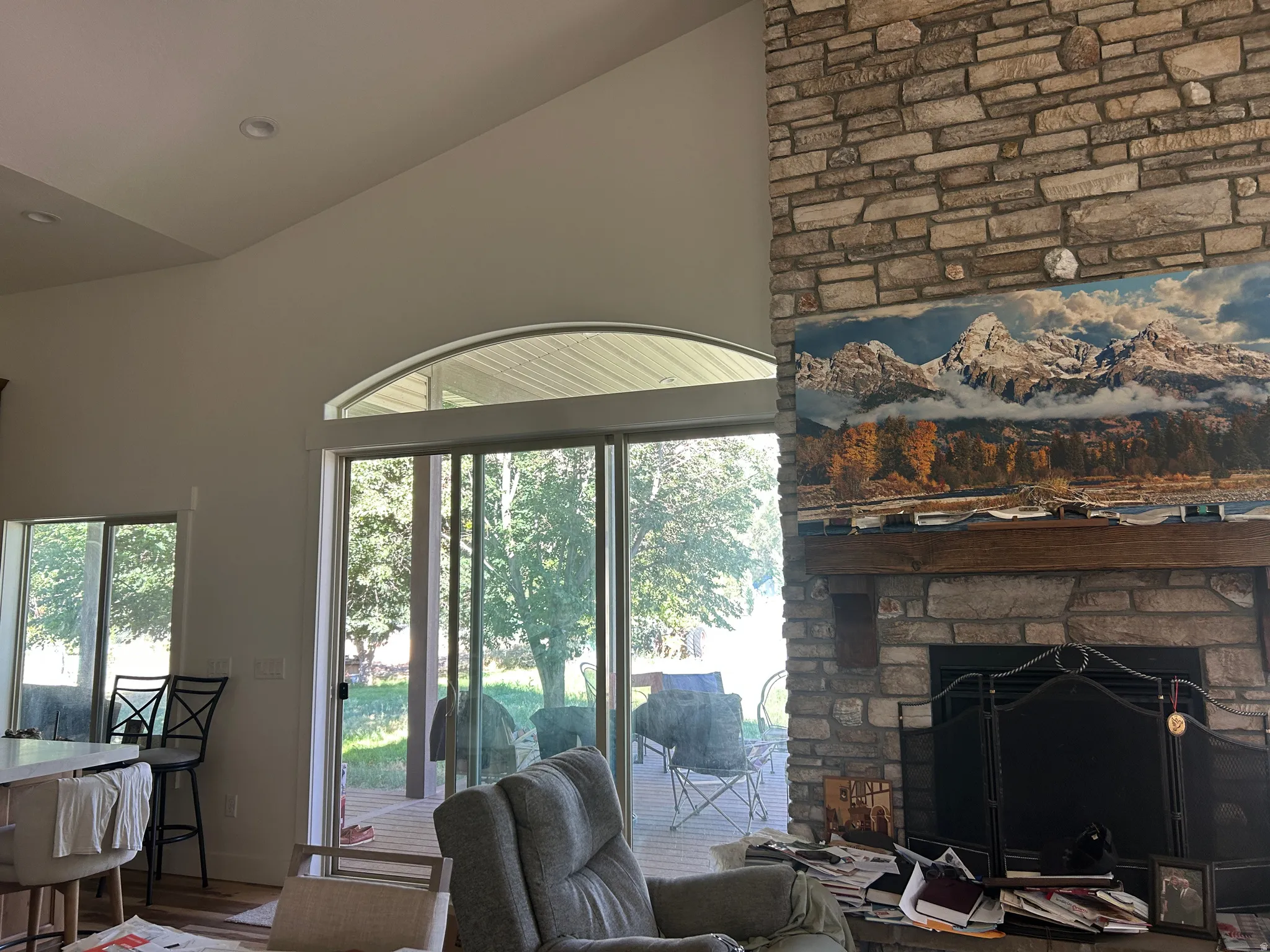 Stone fireplace with a substantial wood mantel, featuring a built-in fire screen