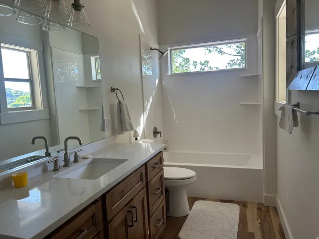 Bathroom featuring wood-finish flooring, a vanity with a light-colored countertop, and a built-in tub with a shower fixture