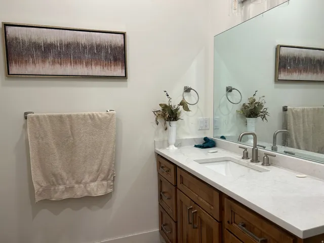 Bathroom vanity featuring a light-colored countertop, an undermount sink, and a brushed nickel faucet