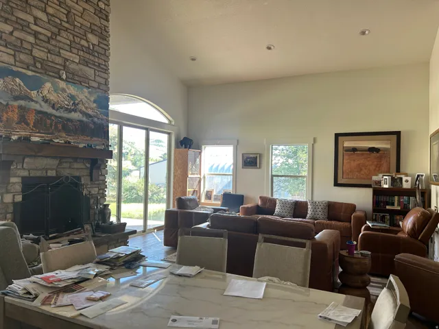 Vaulted ceiling great room featuring a floor-to-ceiling stone fireplace, a substantial wood mantel, recessed lighting, and large sliding glass doors with an arch transom
