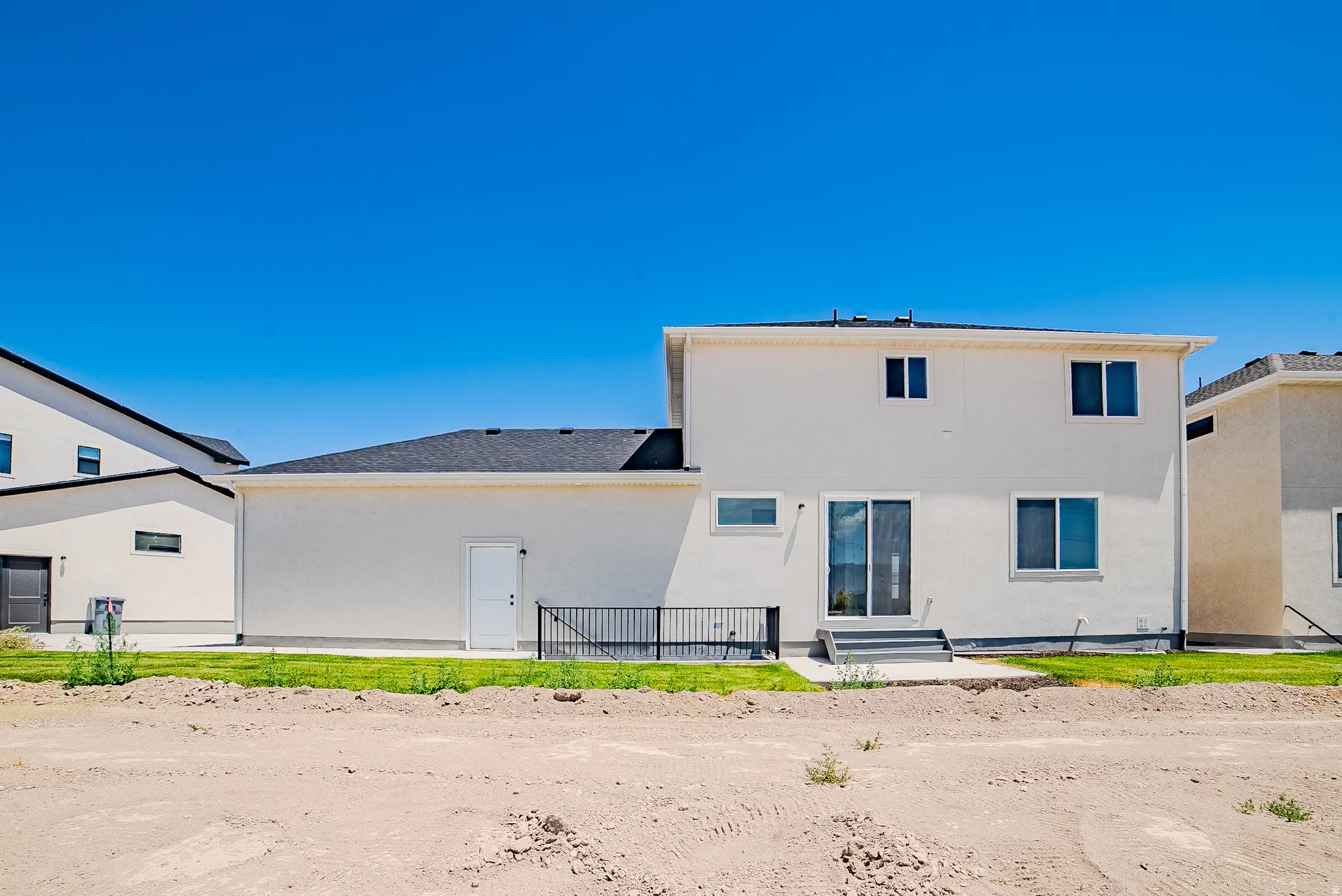 Rear exterior showcasing a multi-level design with stucco siding and a dark shingle roof
