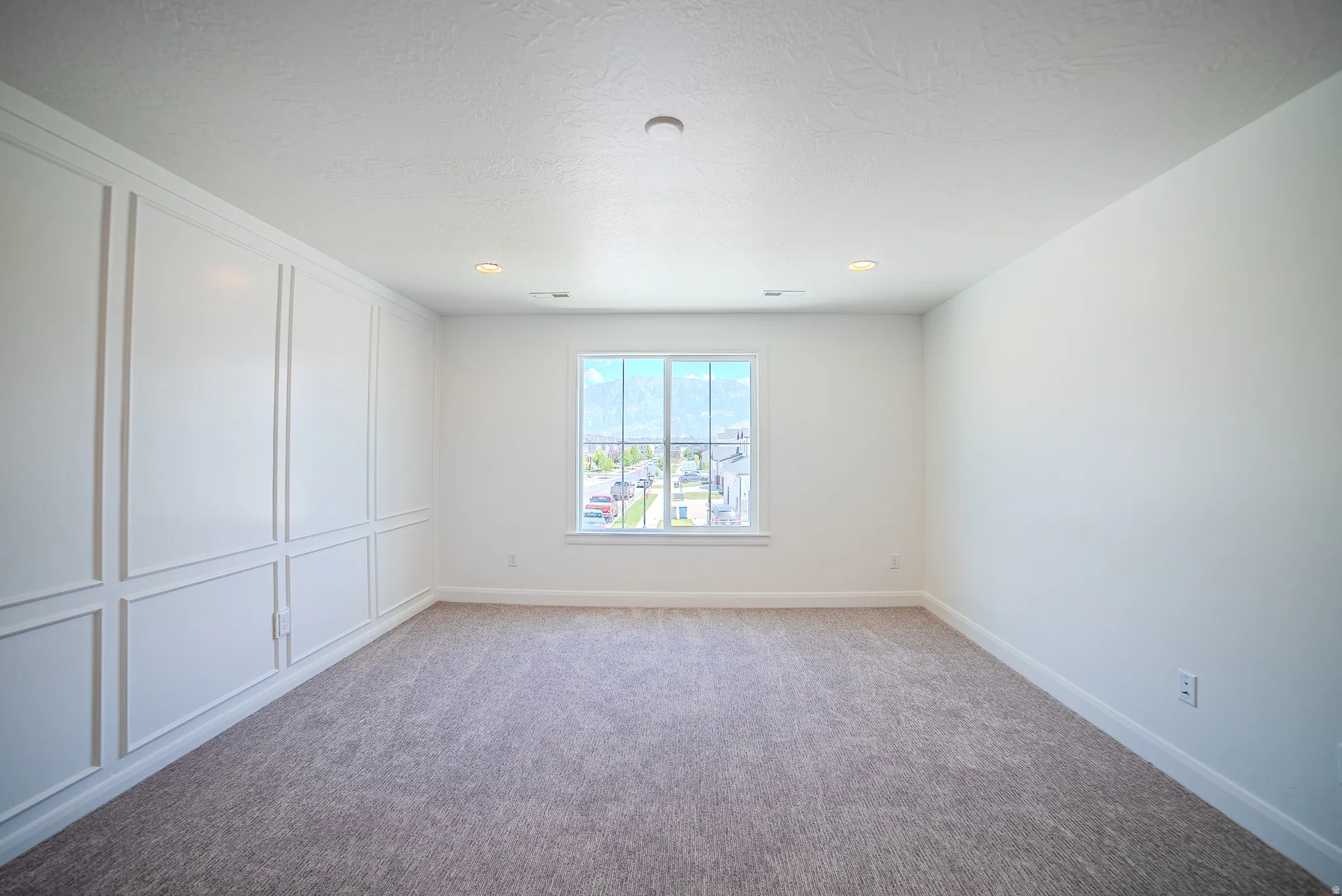 Neutral wall colors featuring a decorative wall panel accent, recessed lighting, double-pane window, and carpet flooring