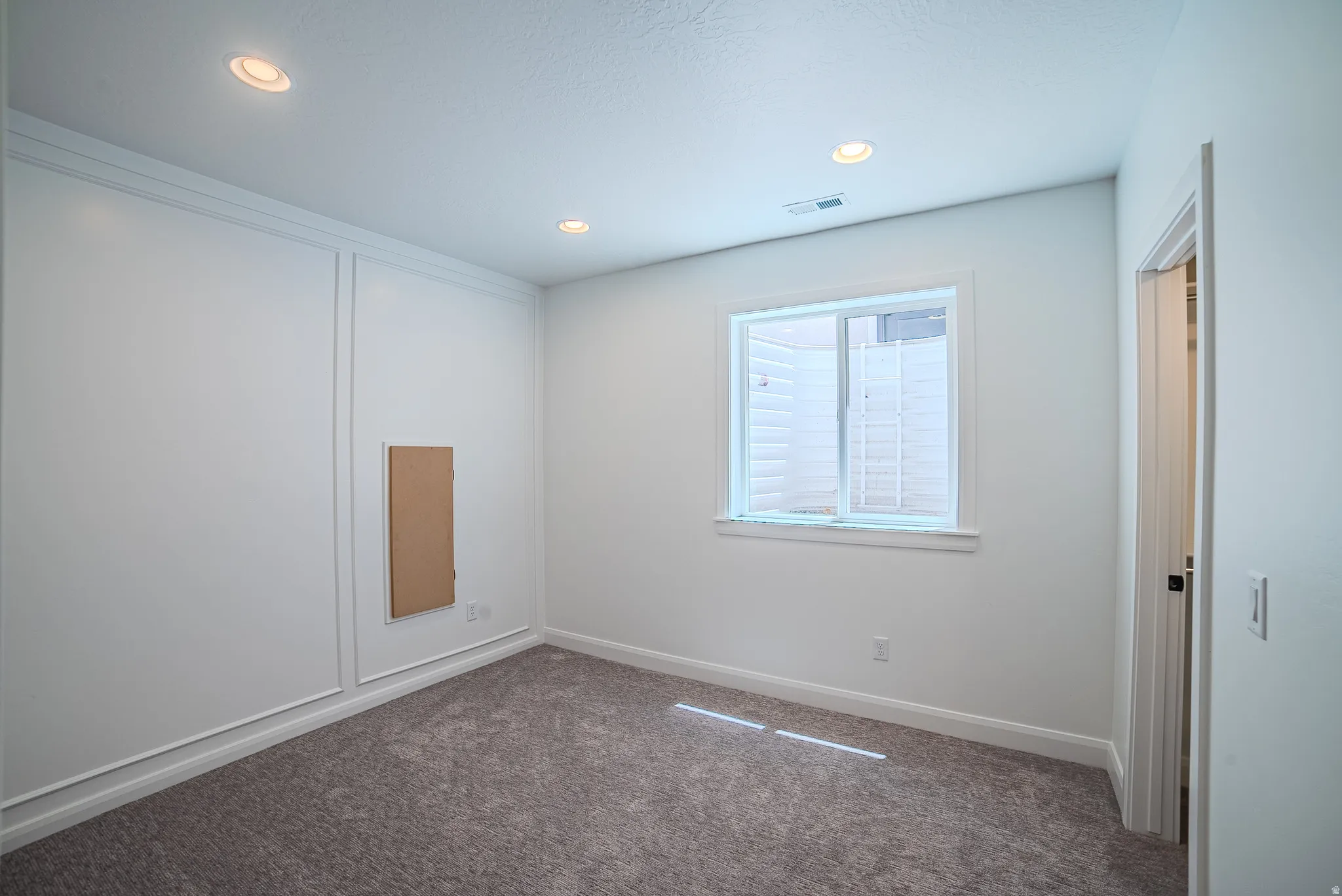 Carpeted room with recessed lighting, a window, and white trim molding