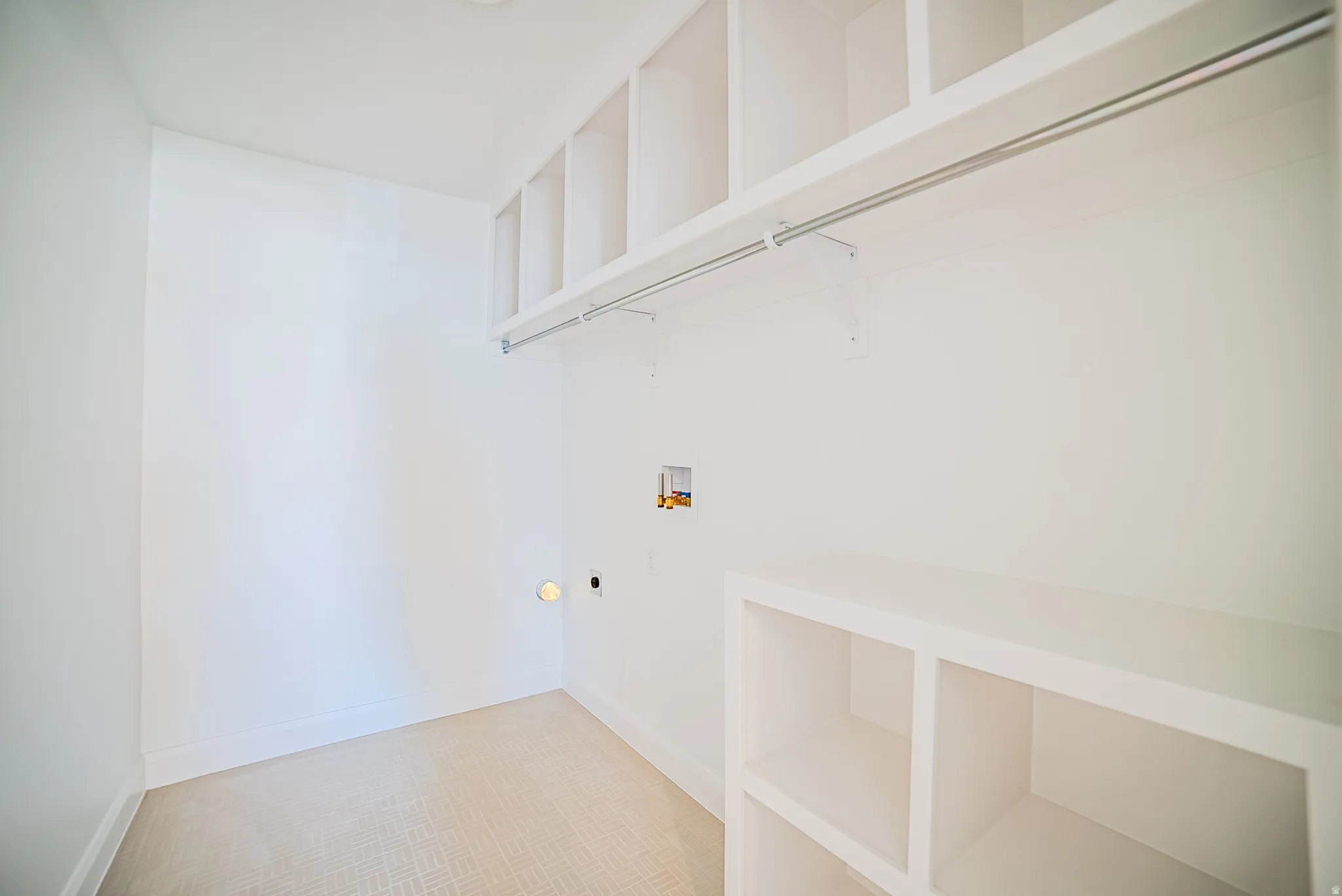 Dedicated utility space featuring built-in white shelving, a chrome hanging rod, and light-toned patterned carpeting