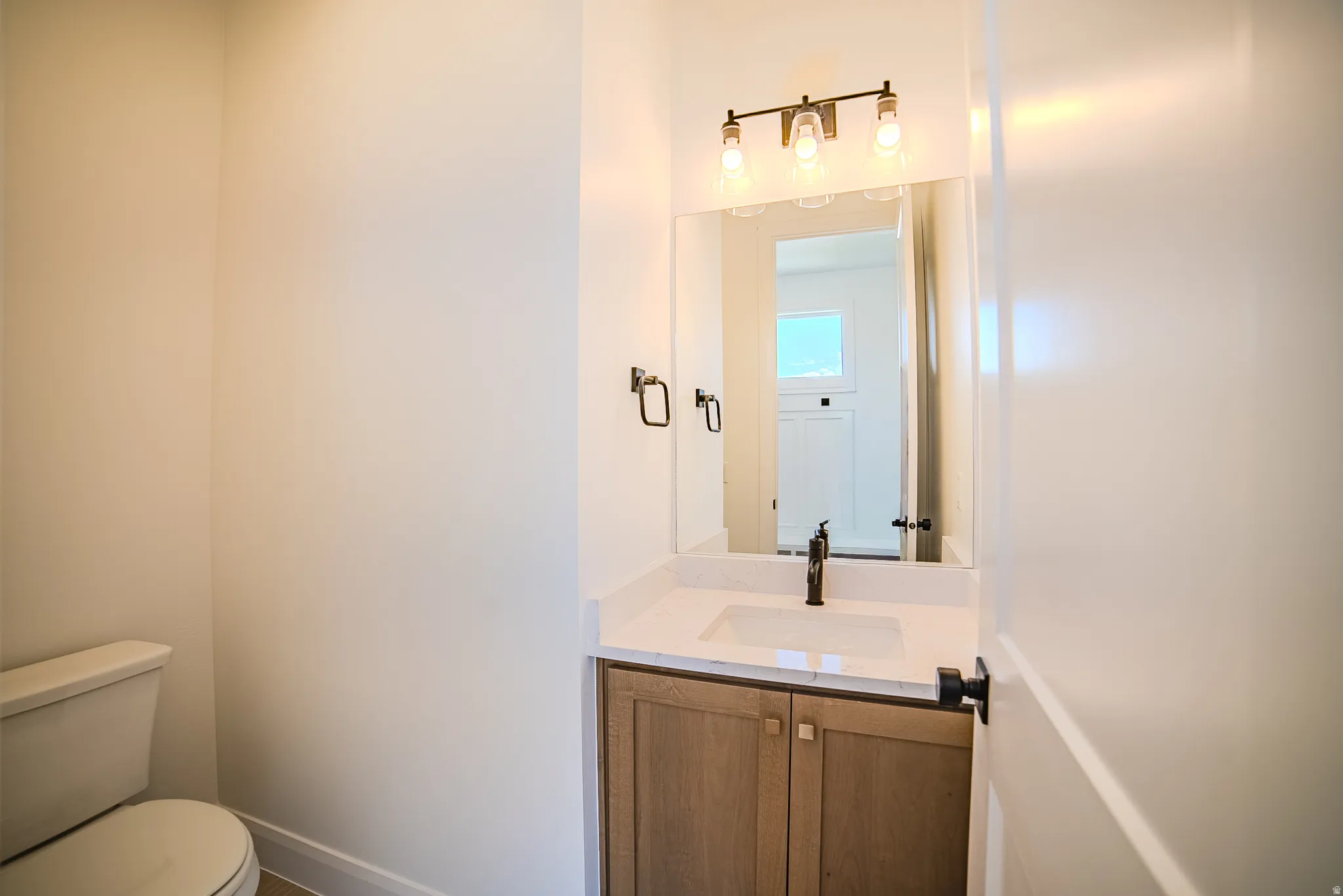Vanity featuring a wood-finish base cabinet, integrated sink, and light-toned countertop