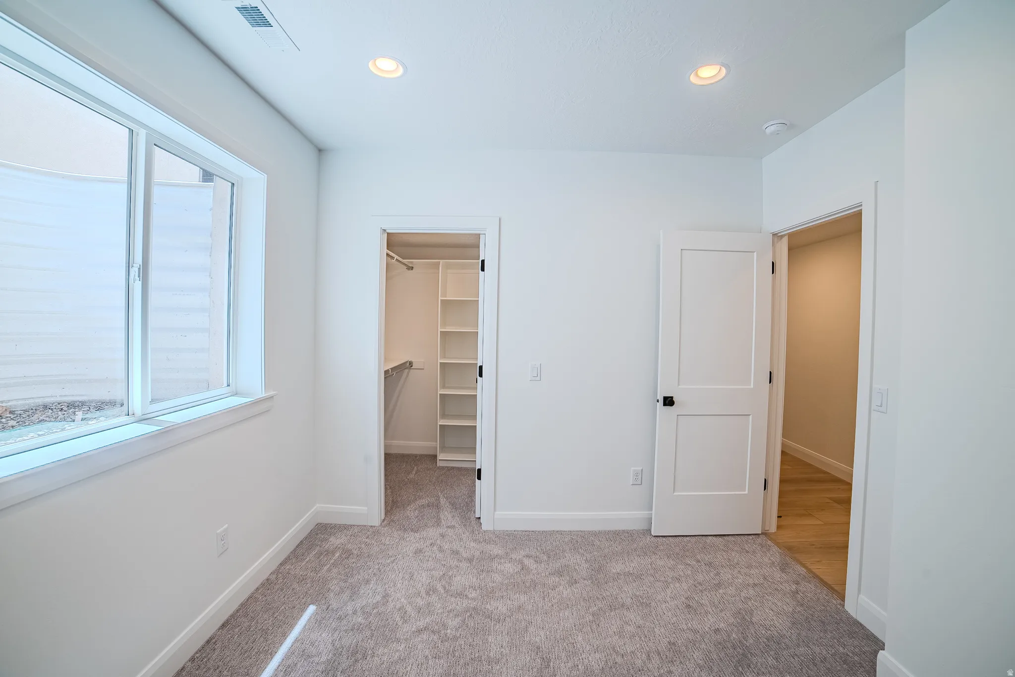 Spacious room featuring neutral carpeting, a large window, and recessed lighting