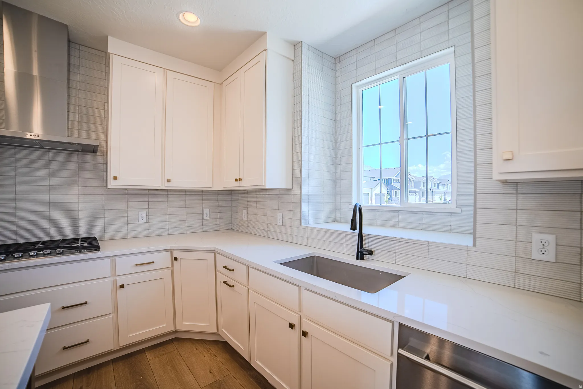 Modern kitchen featuring white shaker cabinetry, light-toned countertops, and wood-finish flooring