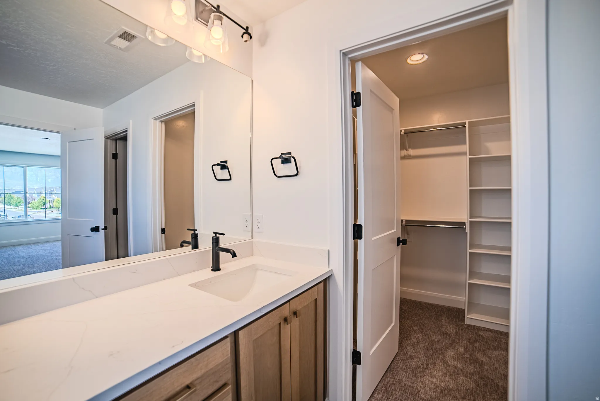 Bathroom vanity featuring a single basin sink, light-toned countertop, and wood-finish cabinetry