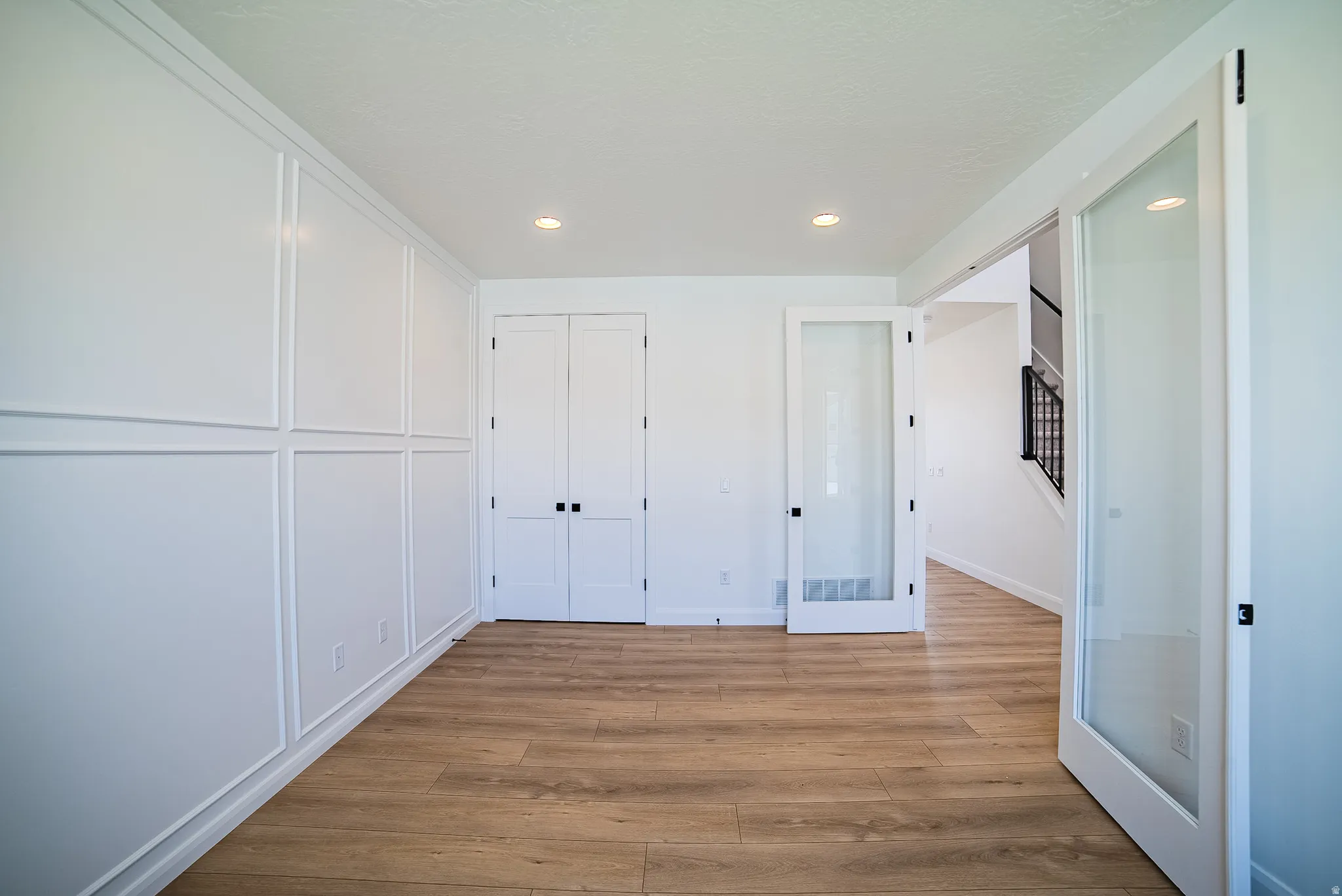 Interior room featuring wood-finish flooring, recessed lighting, and wainscoting