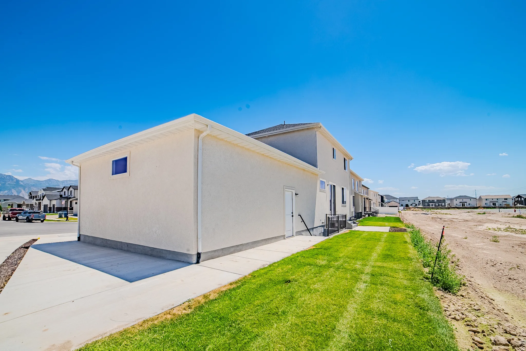 White stucco exterior with a dark roof and a side-entry door