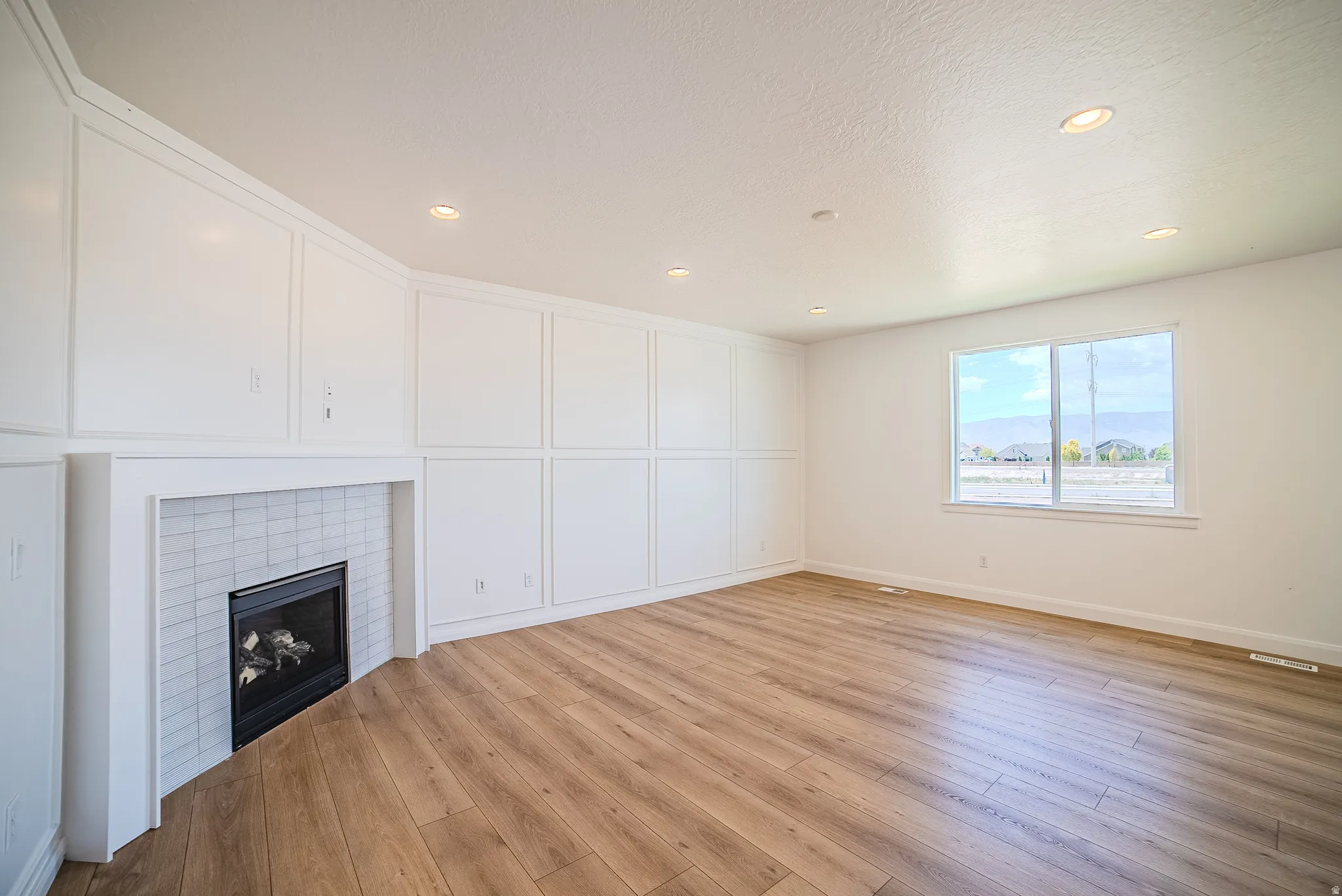 Spacious room featuring wood-finish flooring, recessed lighting, and a window with a mountain backdrop