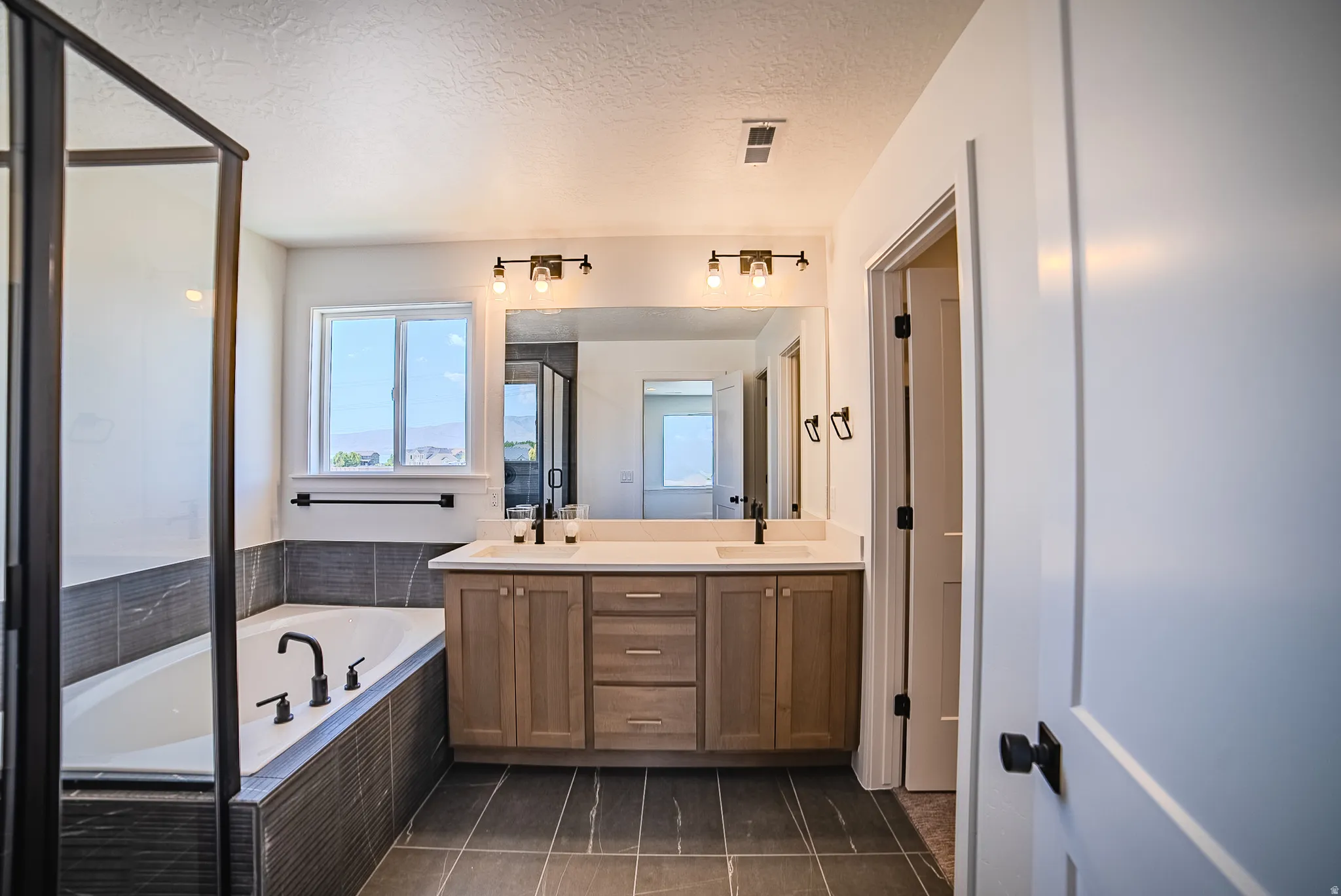 Bathroom with a double vanity featuring a light wood-finish cabinet and white countertop