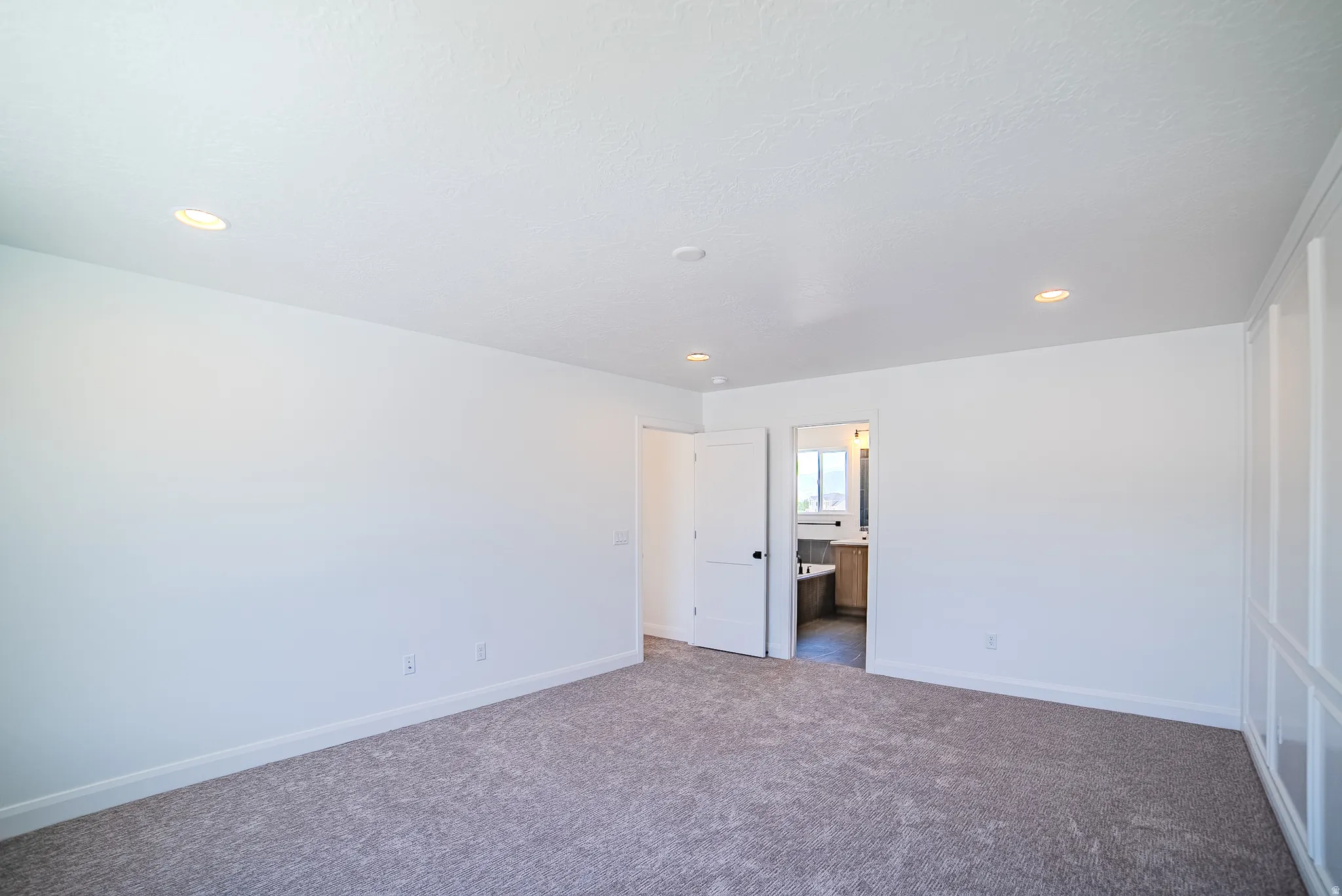 Spacious room with gray carpet flooring and recessed lighting
