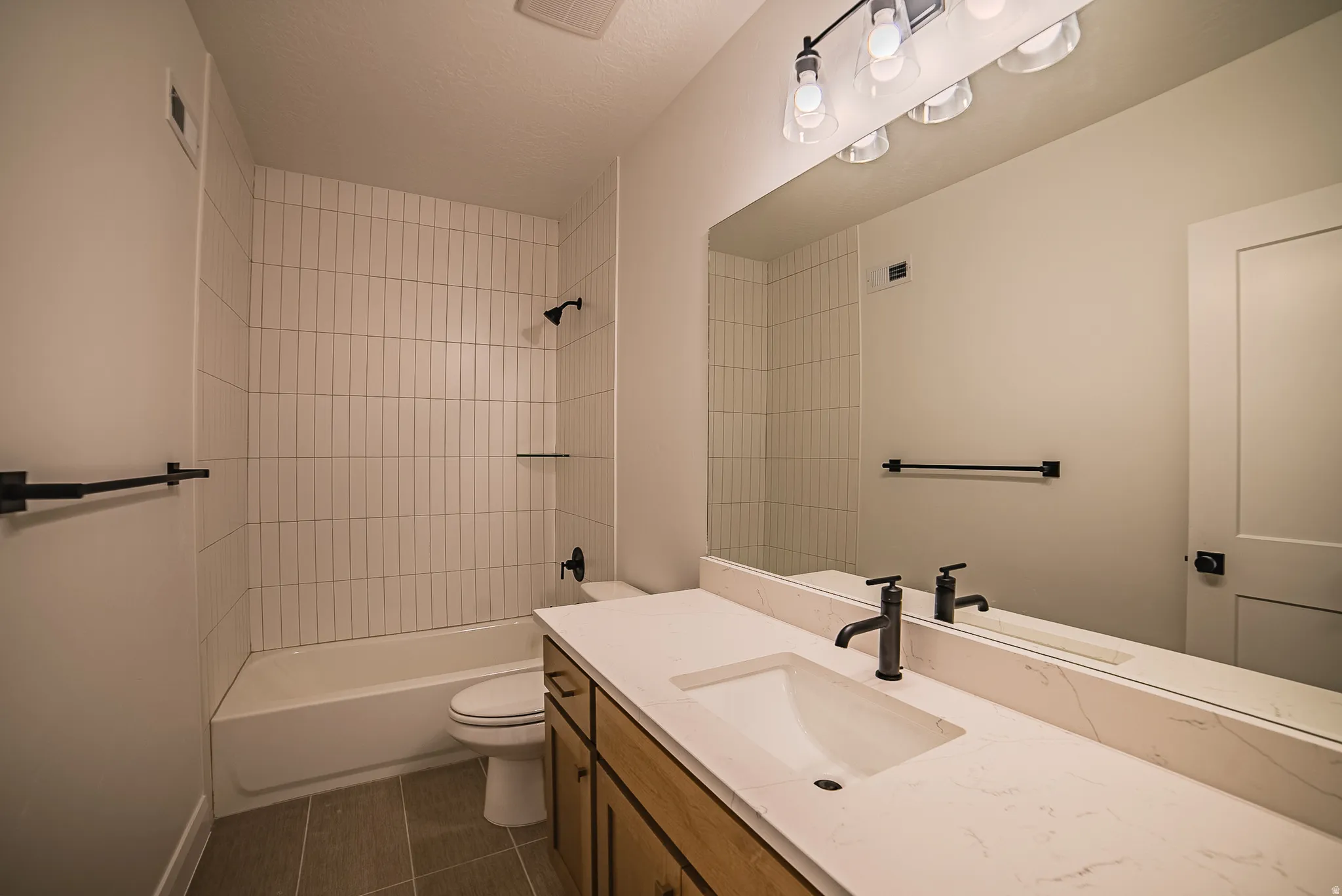 Modern bathroom featuring a single vanity with wood-finish cabinetry, a large integrated mirror, and a white countertop with an undermount sink