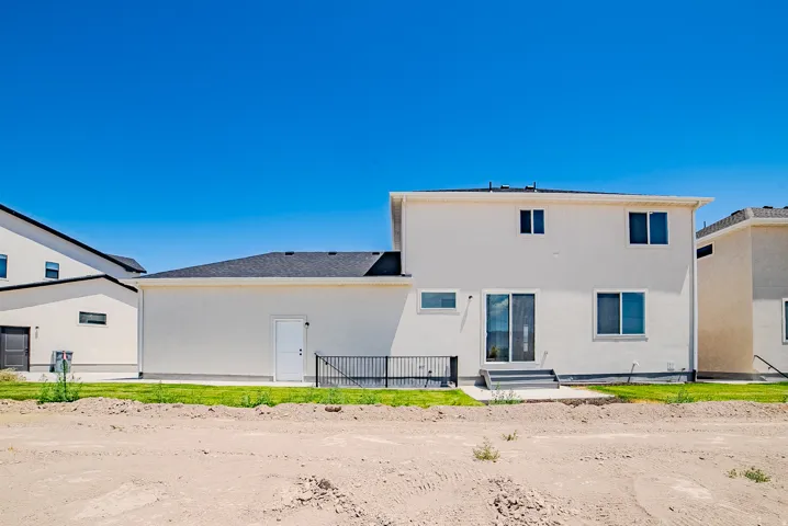 Rear exterior showcasing a multi-level design with stucco siding and a dark shingle roof