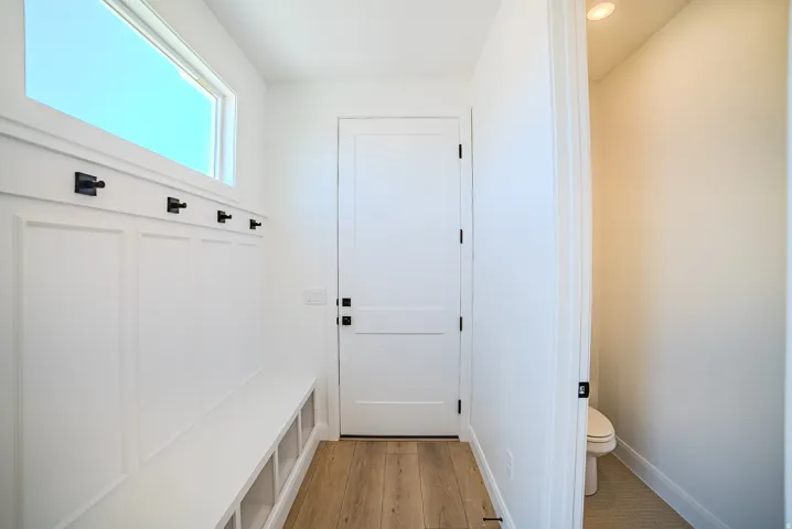 Mudroom featuring a built-in bench with storage cubbies, wainscoting, and black wall hooks