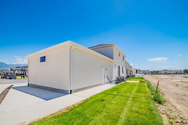White stucco exterior with a dark roof and a side-entry door