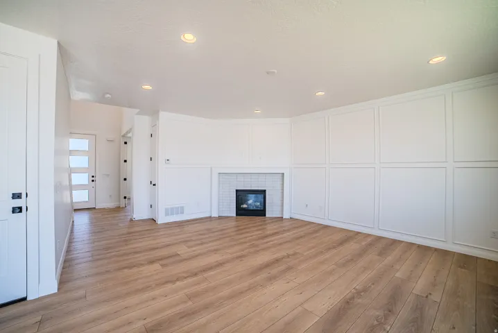 Spacious room featuring wood-finish flooring, recessed lighting, and a contemporary fireplace with white subway tile surround