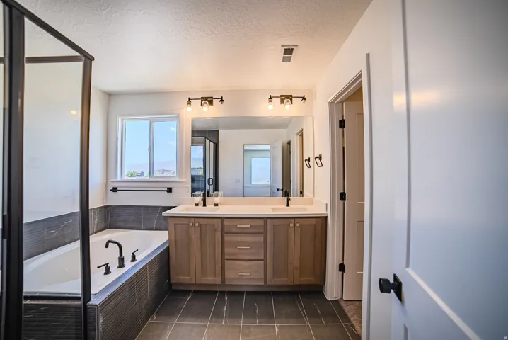 Bathroom with a double vanity featuring a light wood-finish cabinet and white countertop