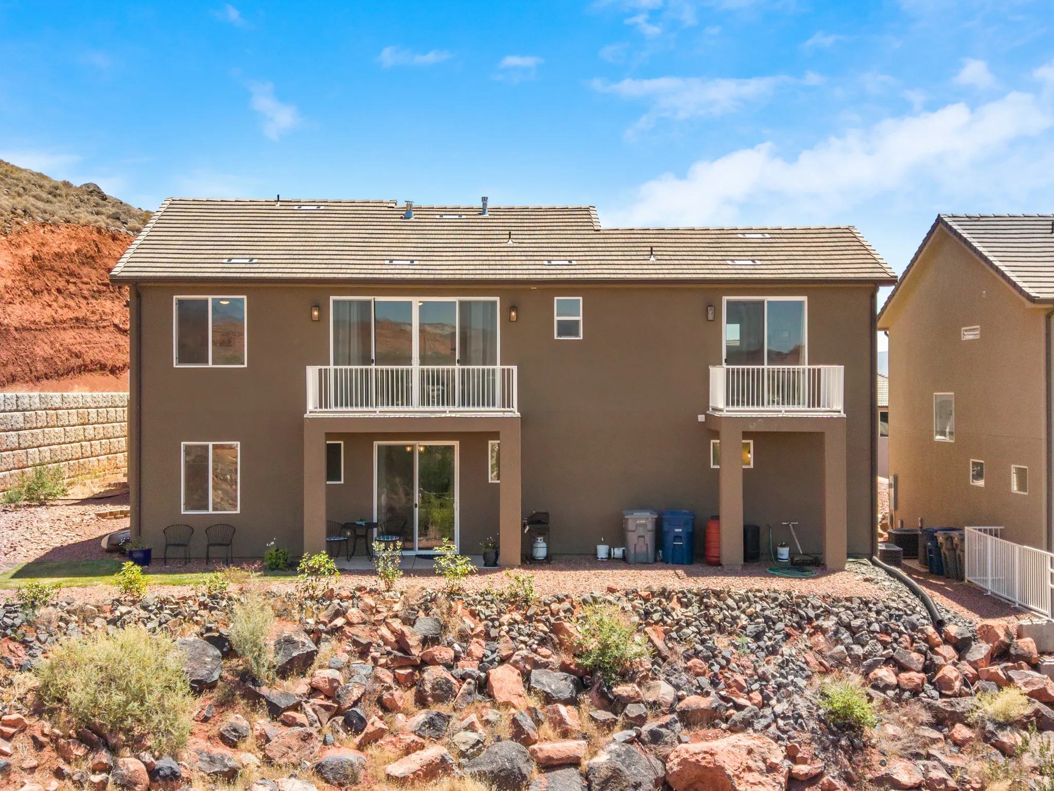 Two-story exterior featuring a brown stucco finish and a light-colored tile roof