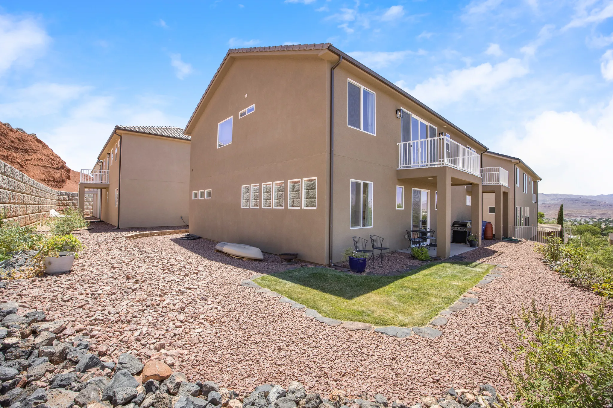 Rear exterior of a multi-level residence featuring a stucco facade and white-framed windows