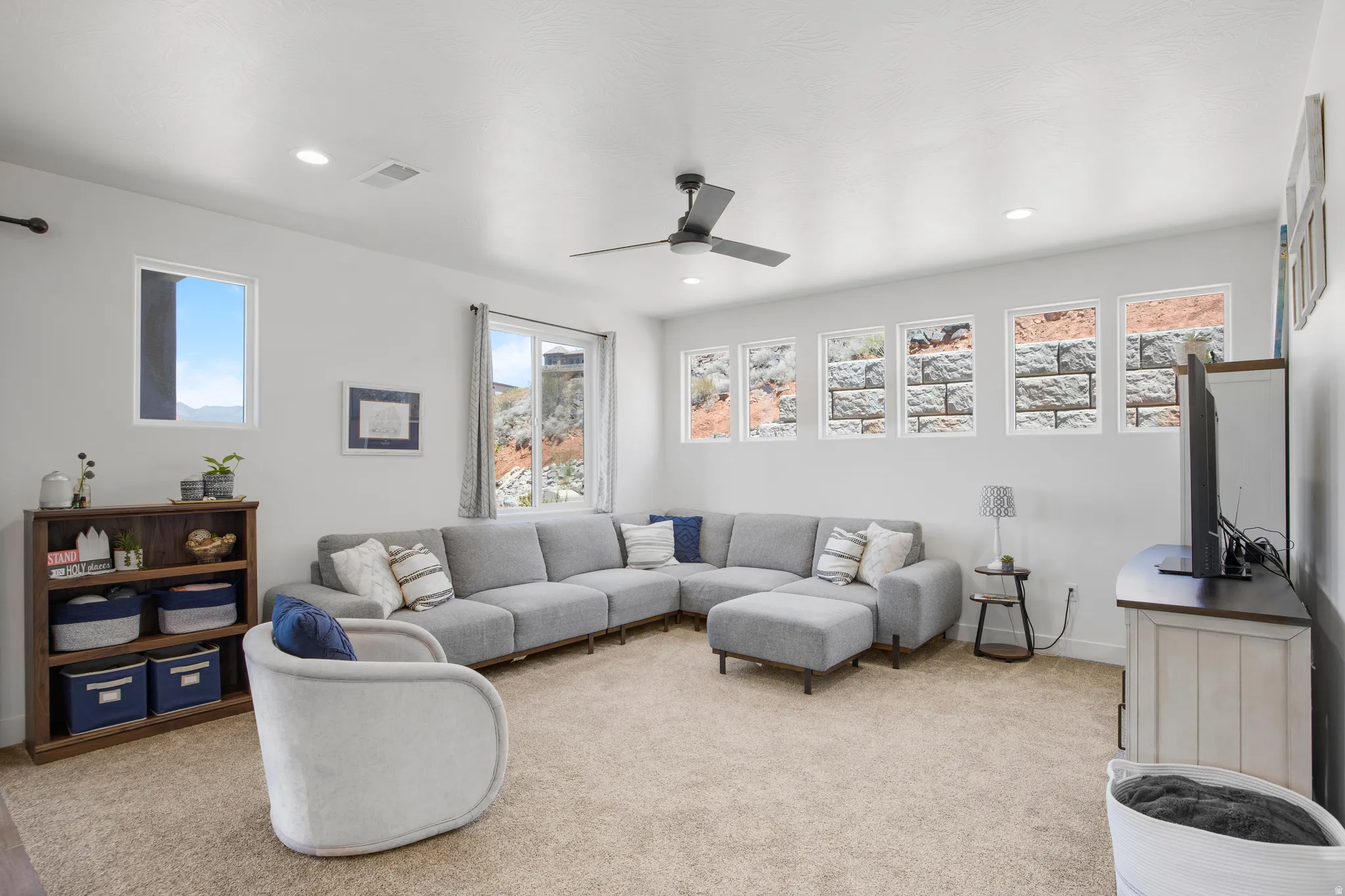 Bright living space with recessed lighting and a ceiling fan