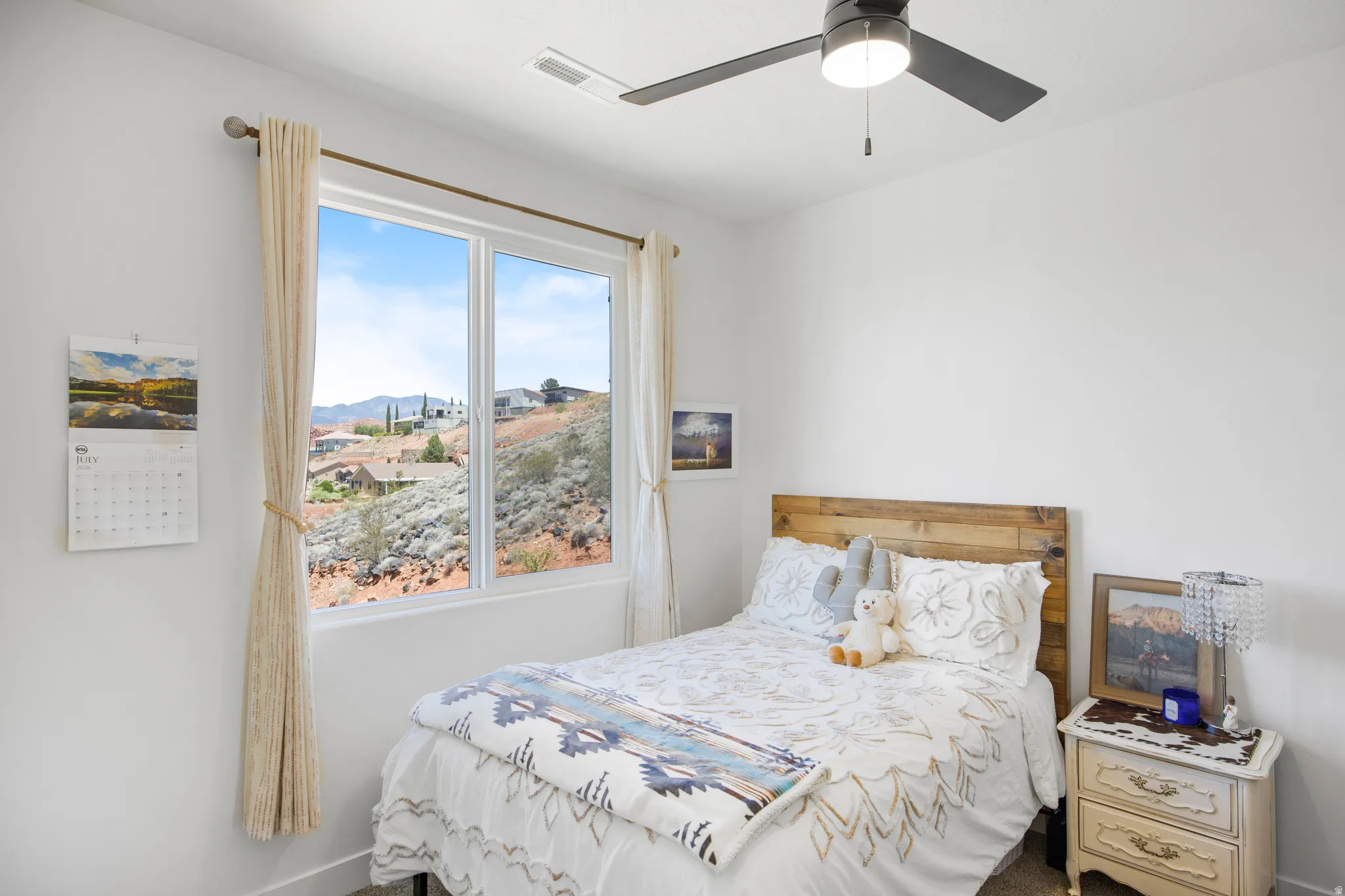 Bedroom featuring a large window, a wood-finish headboard, and a ceiling fan with integrated lighting