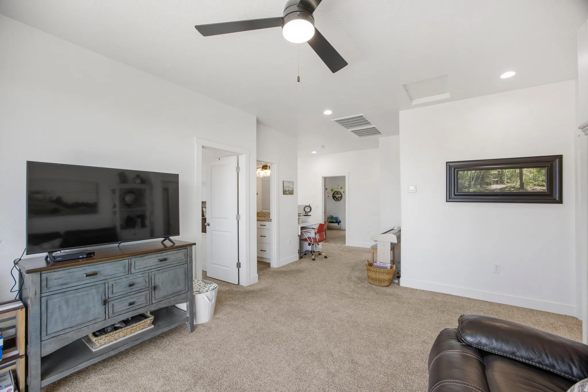 Carpeted living area featuring a ceiling fan with integrated lighting, recessed lighting, and white walls