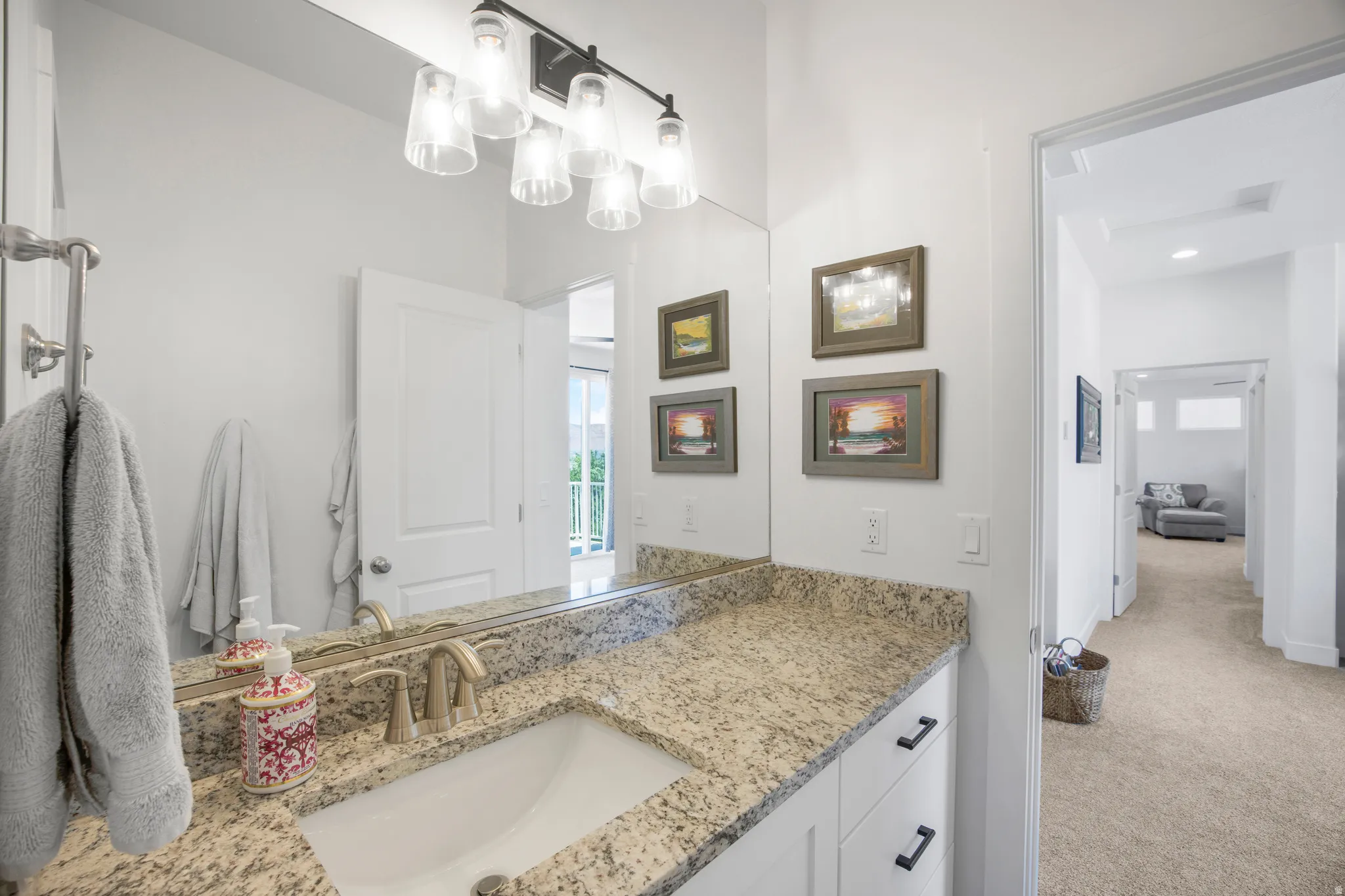 Bathroom vanity featuring a light-toned countertop, a rectangular undermount sink with a brushed nickel faucet, and a wall-mounted mirror