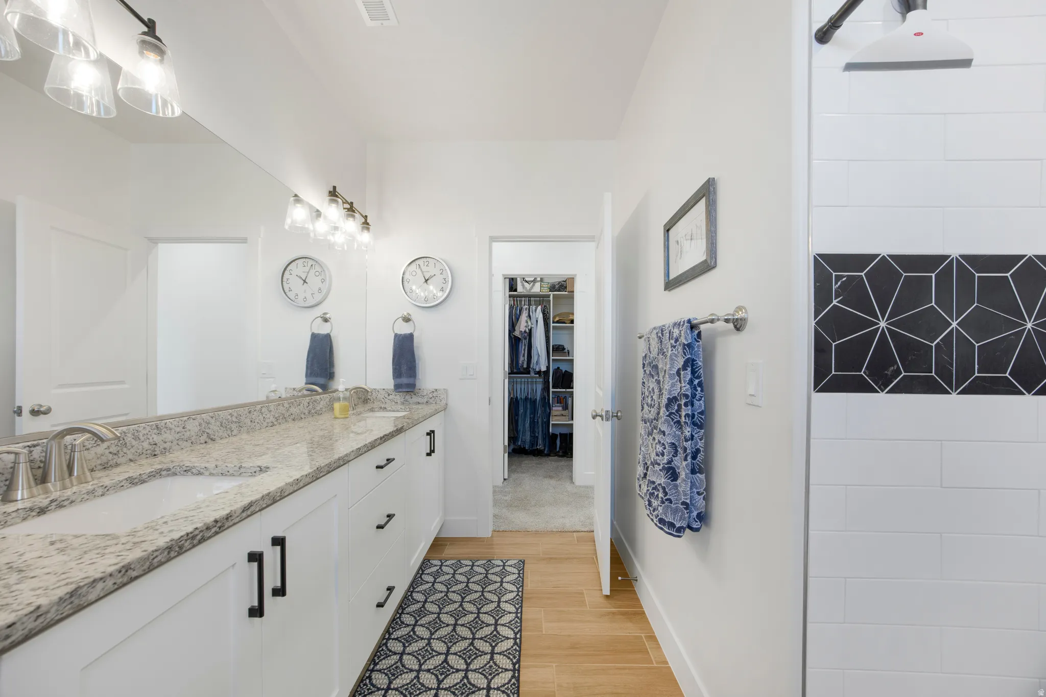 Double vanity with a granite countertop, undermount sinks, and white shaker-style cabinetry