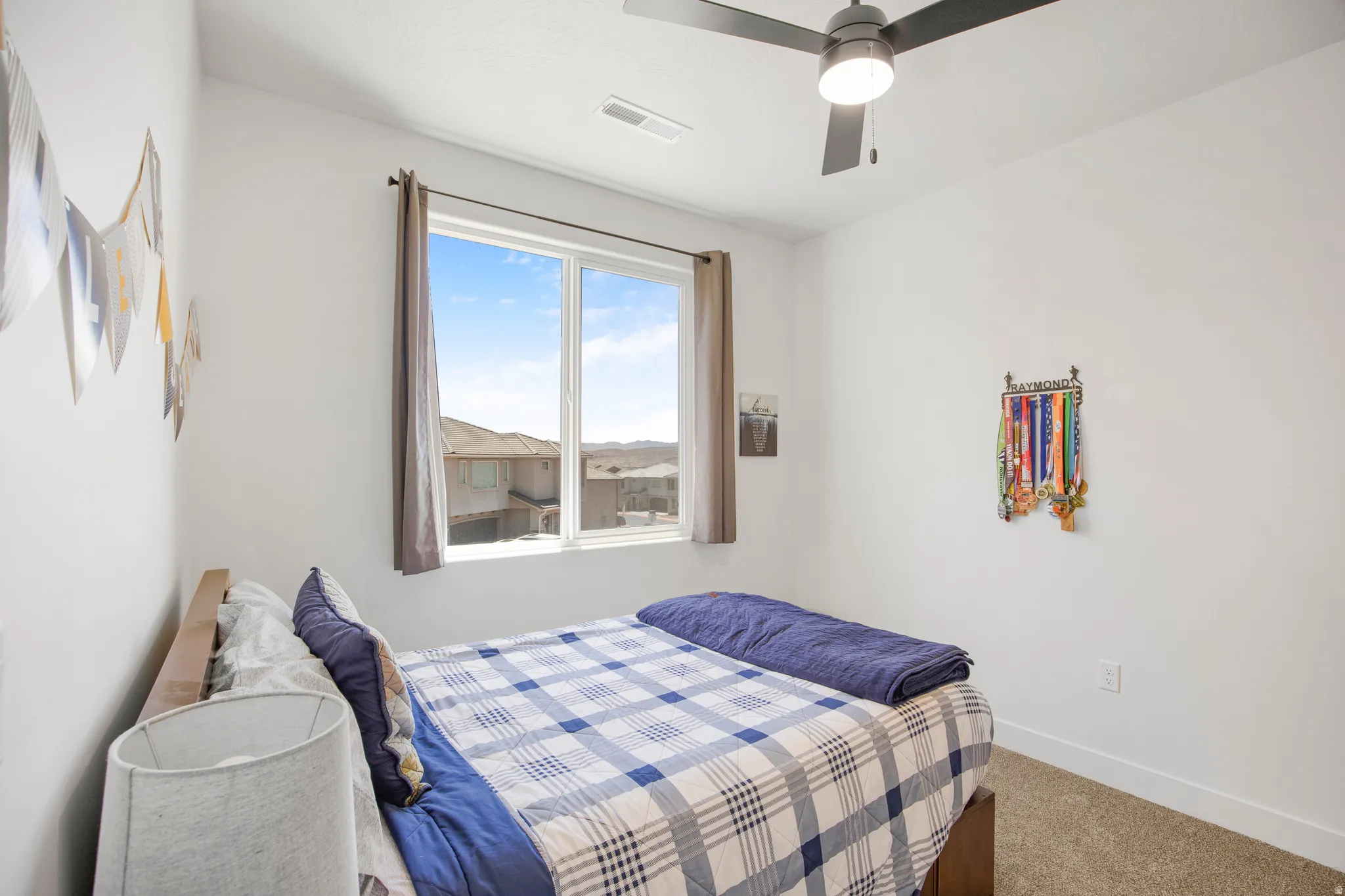 Bright room featuring a large window, a modern ceiling fan with integrated lighting, clean white walls, and a neutral-toned carpet