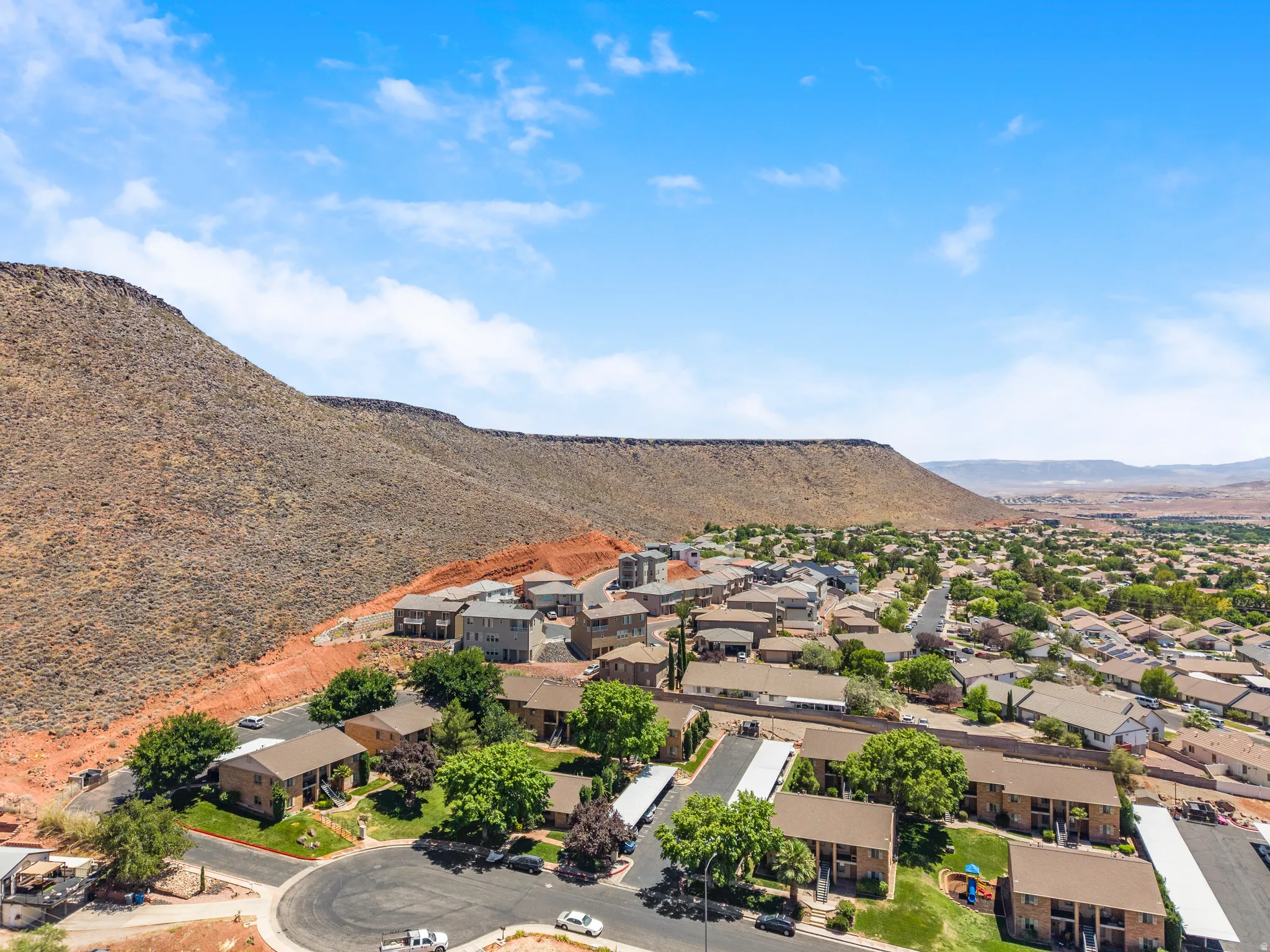 Aerial perspective showcasing a residential community nestled at the base of a prominent mountain