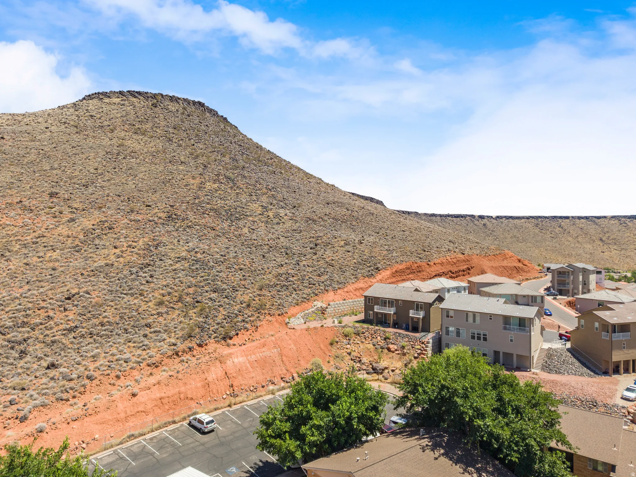 Multi-story residential buildings with balconies situated at the base of a rugged mountain
