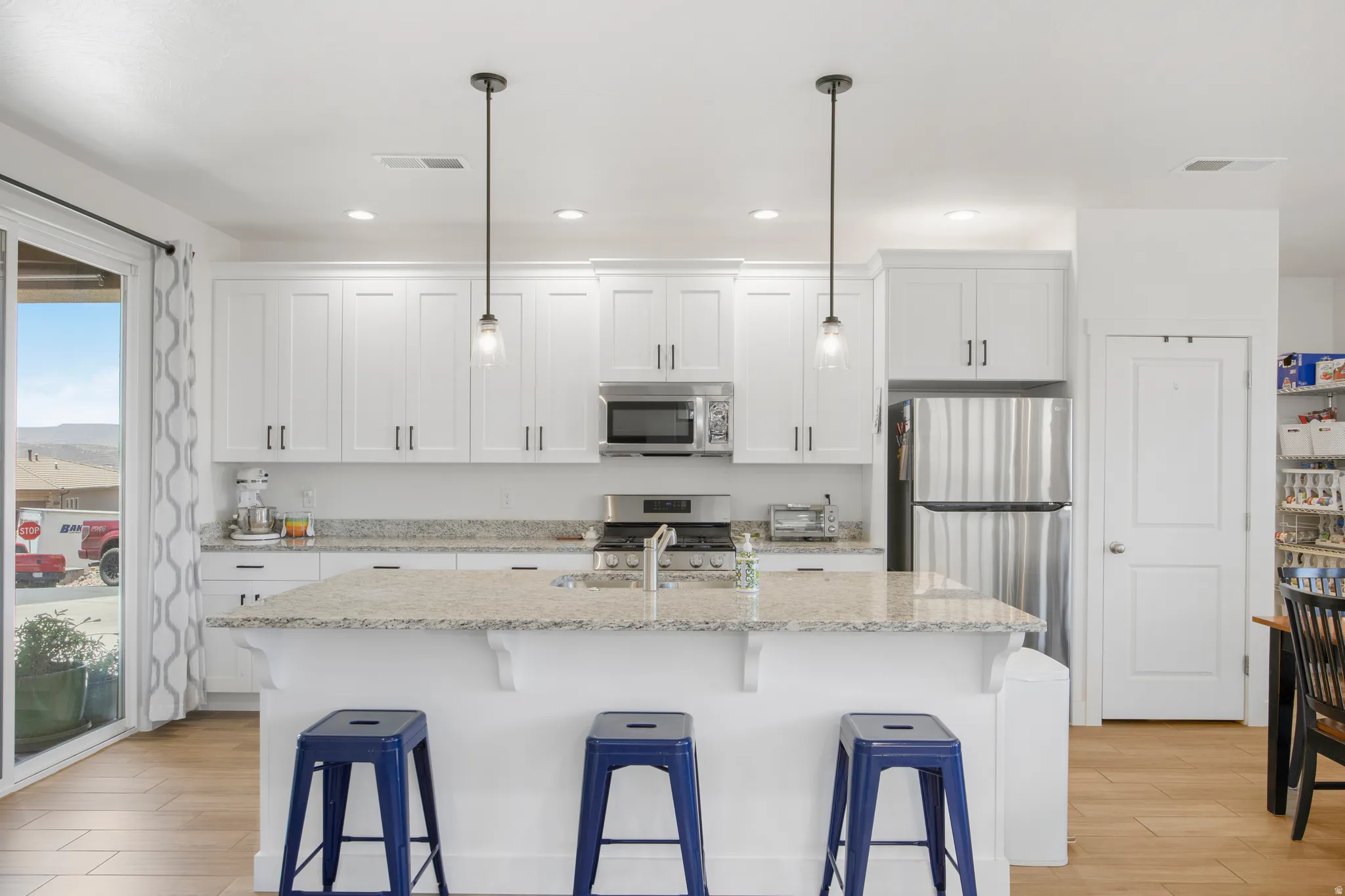 Kitchen featuring a large central island with seating, white shaker cabinetry, stainless steel appliances, and granite countertops