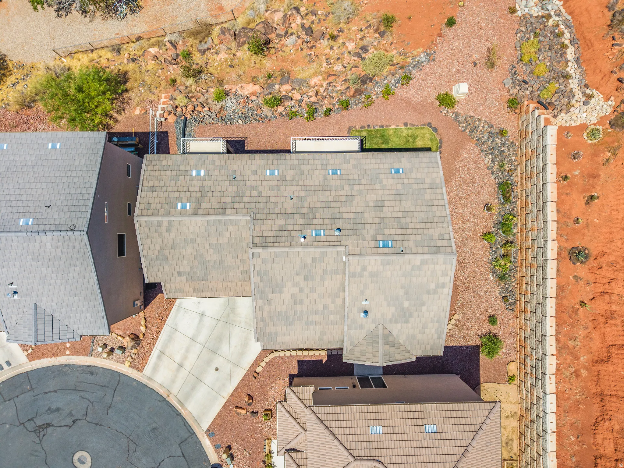 Aerial depiction of a property featuring multi-level roofing, skylights, and a concrete driveway