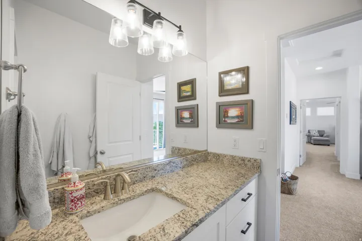 Bathroom vanity featuring a light-toned countertop, a rectangular undermount sink with a brushed nickel faucet, and a wall-mounted mirror