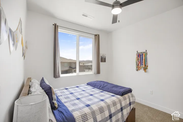 Bright room featuring a large window, a modern ceiling fan with integrated lighting, clean white walls, and a neutral-toned carpet