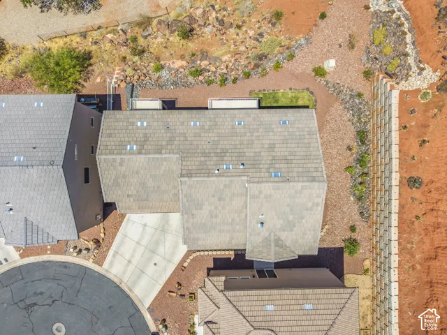 Aerial depiction of a property featuring multi-level roofing, skylights, and a concrete driveway