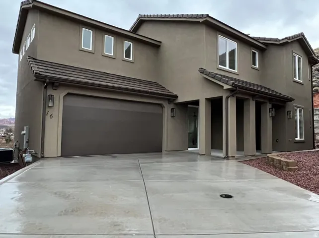 Stucco exterior with a tiled roof, multi-pane windows, and a covered entry