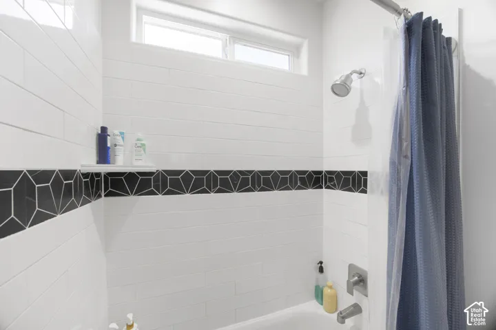 Bathtub-shower combination featuring white subway tile, a decorative black geometric tile accent band, and a brushed nickel shower head and faucet