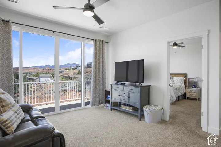 Spacious room with a ceiling fan, light beige carpeting, and a large sliding glass door offering expansive views of the red rock landscape