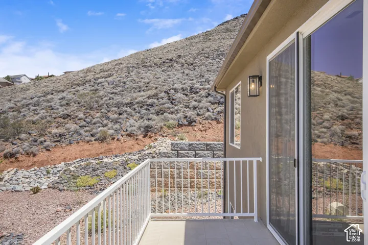 Private balcony featuring a stucco exterior, sliding glass door, white metal railing, and an outdoor wall sconce